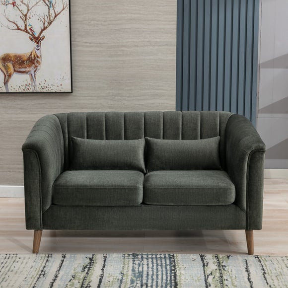 A dark green velvet loveseat sofa , two matching throw pillows, and light wood legs, shown in a styled living room setting.